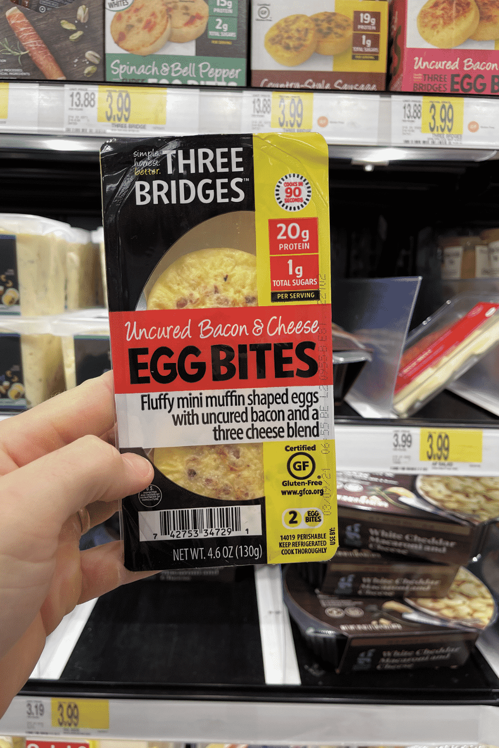 A hand holding a package of bacon and cheese egg bites.