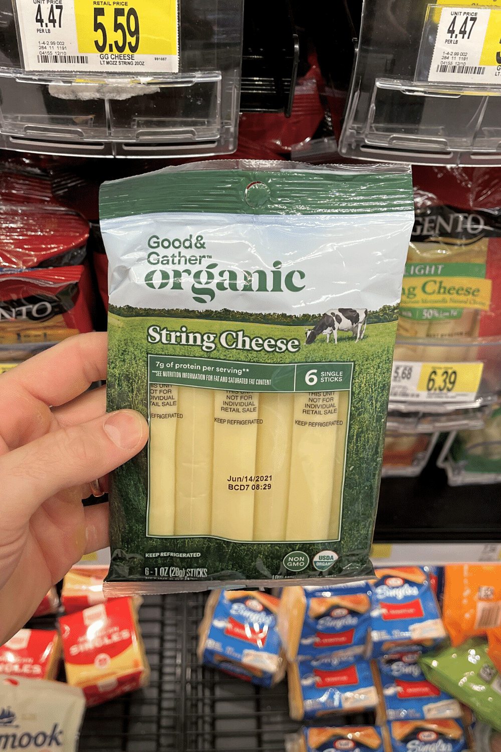 A hand holding a package of string cheese sticks.