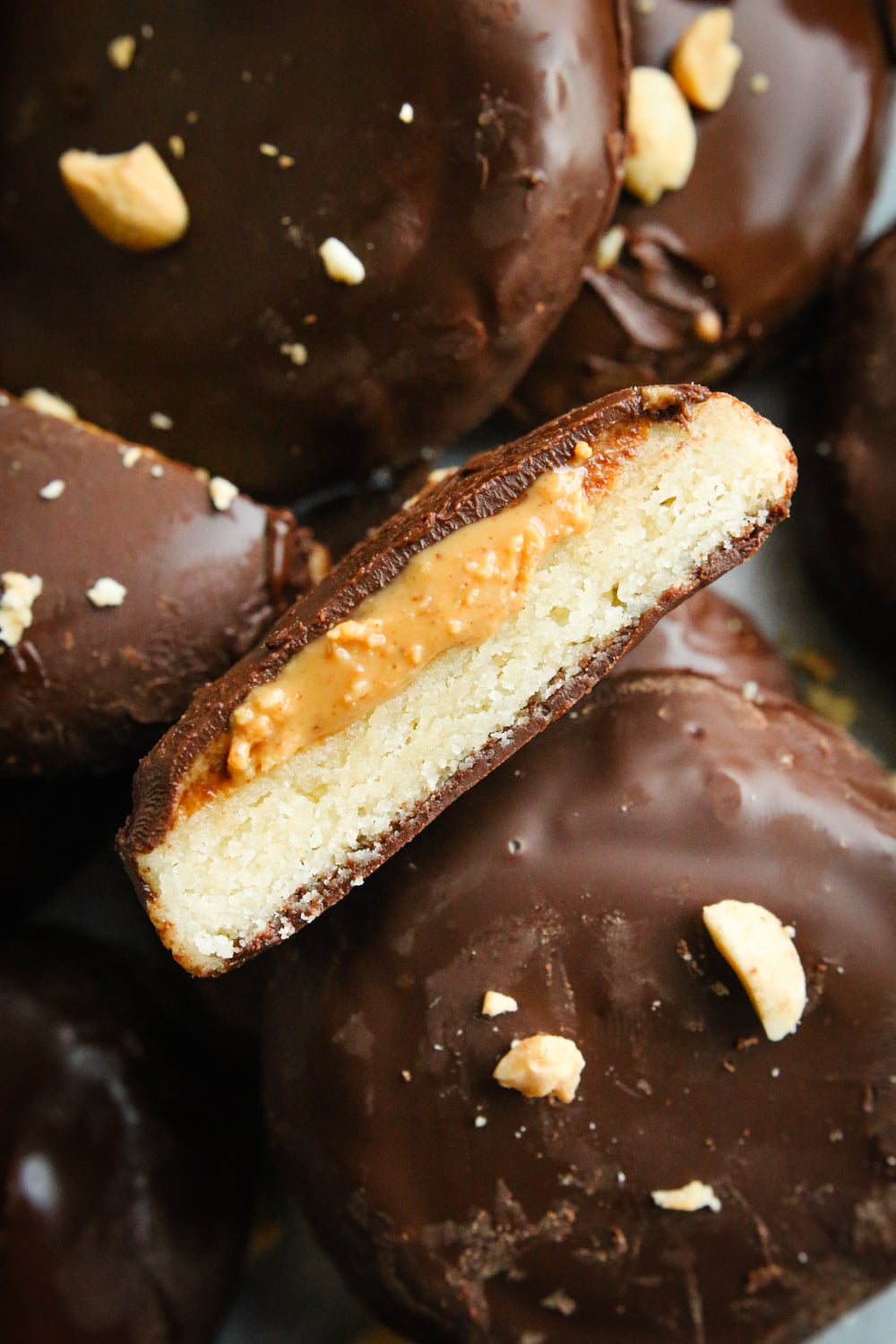 One half of a shortbread cookie that has been covered in chocolate and has peanut butter oozing out of it.