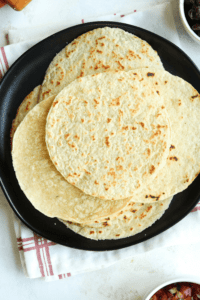 Tortillas stacked on top of one another on a black plate.