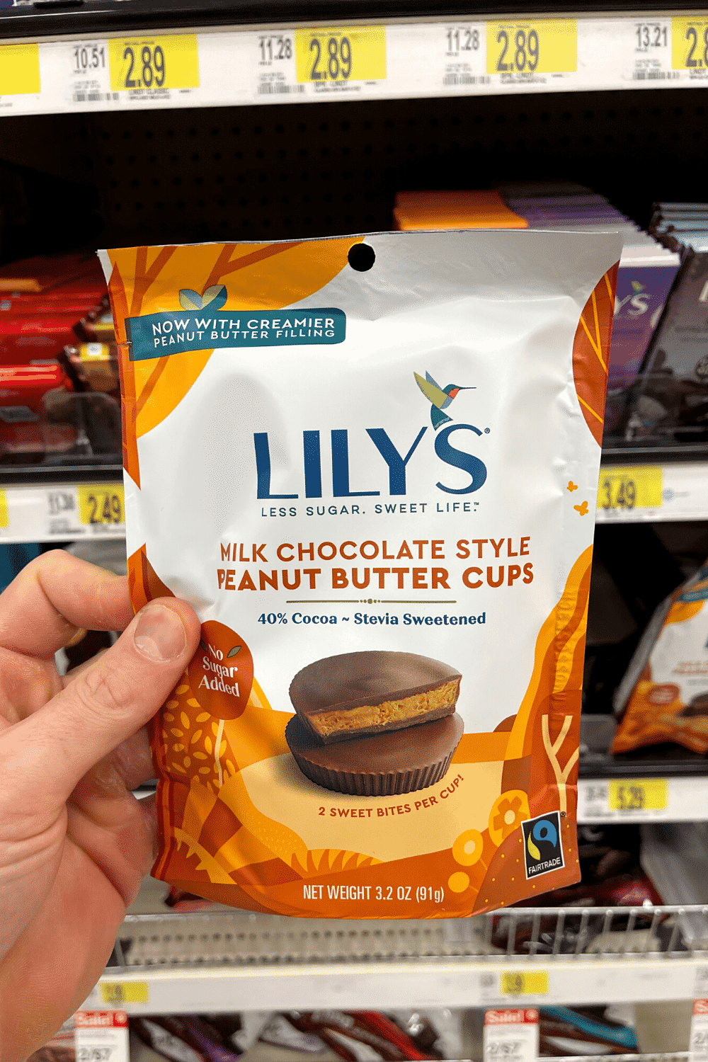 A hand holding a bag of low carb milk chocolate peanut butter cups.