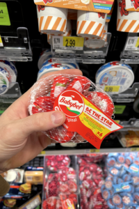 A hand holding a bag of mini cheese wheels.