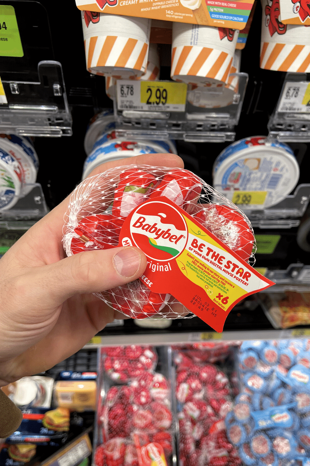 A hand holding a bag of mini cheese wheels.