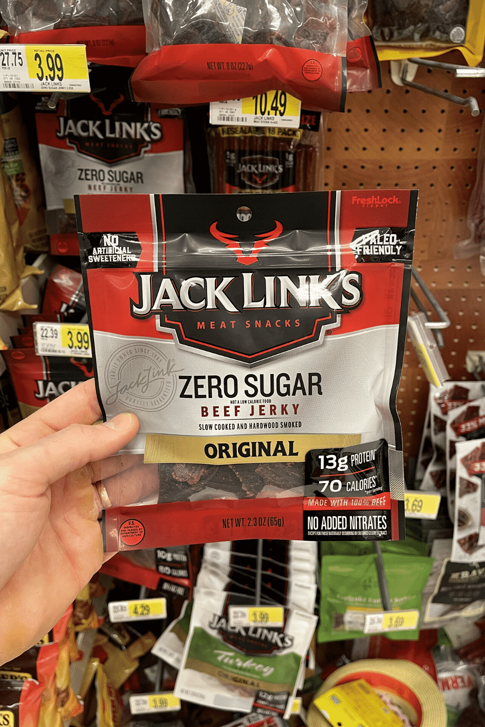 A hand holding a bag of sugar free jerky.