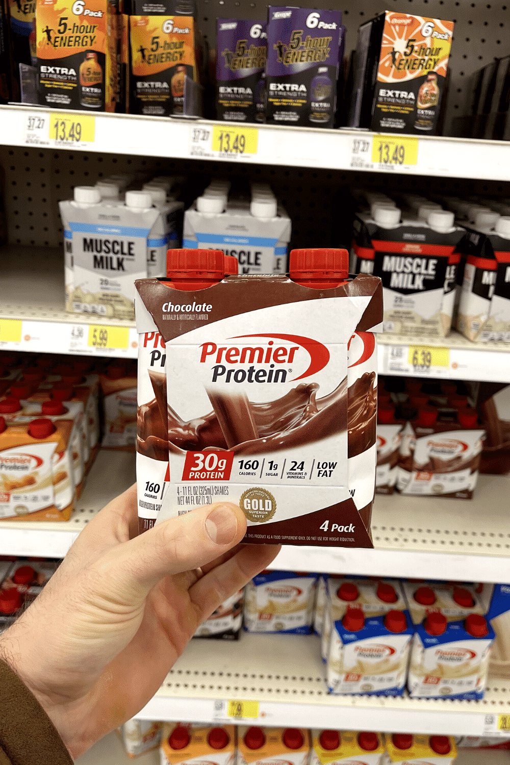 A hand holding a box of protein shakes.