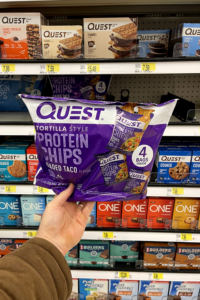 A hand holding a bag of of protein chips.