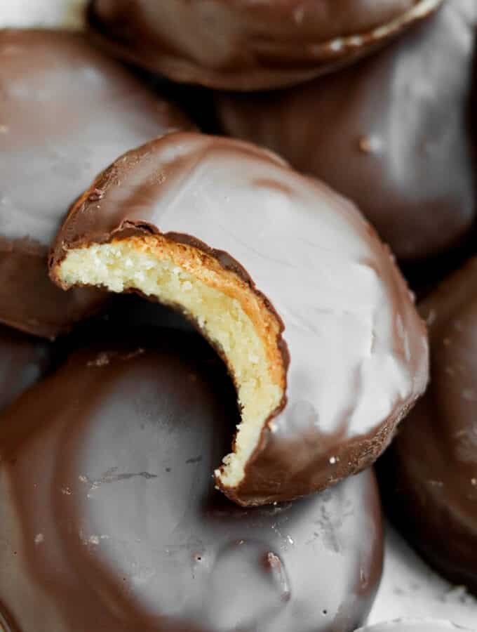 A chocolate covered cookie with a bite taken out of it.