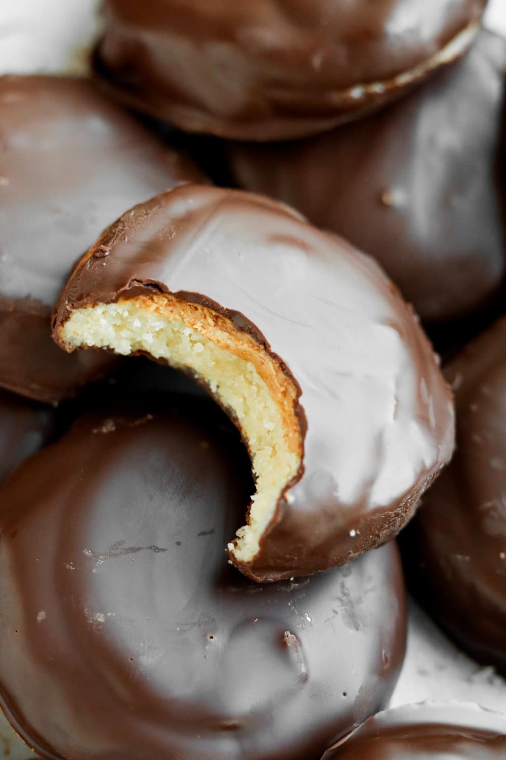 A chocolate covered cookie with a bite taken out of it.