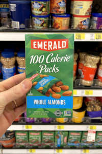 A hand holding a box of almond snack packs.