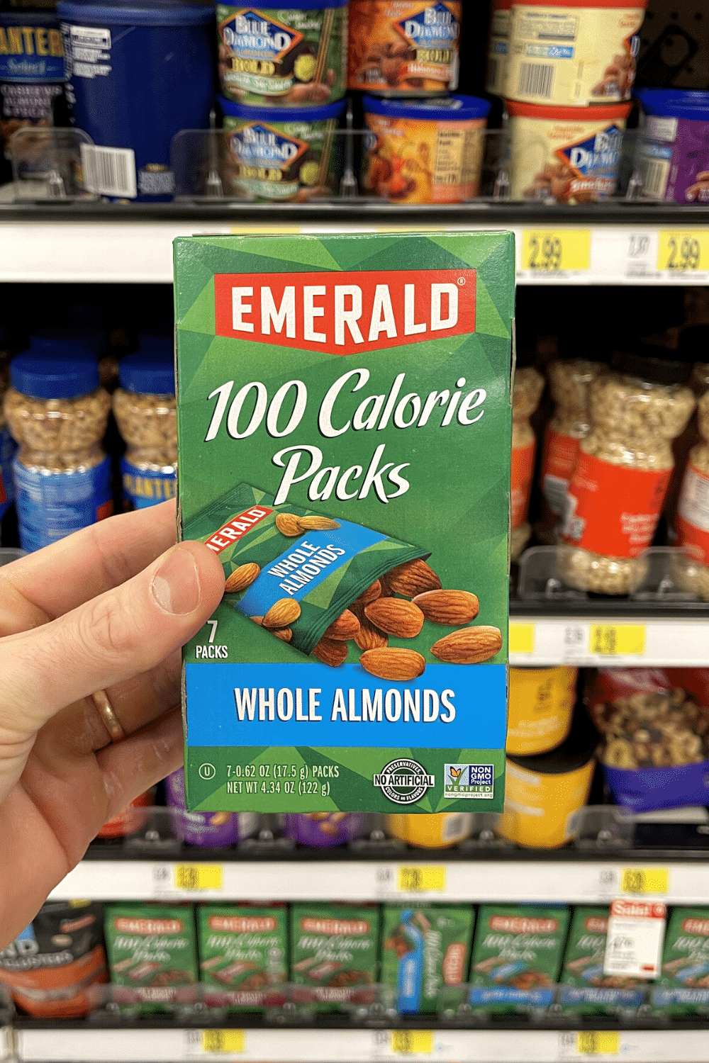 A hand holding a box of almond snack packs.