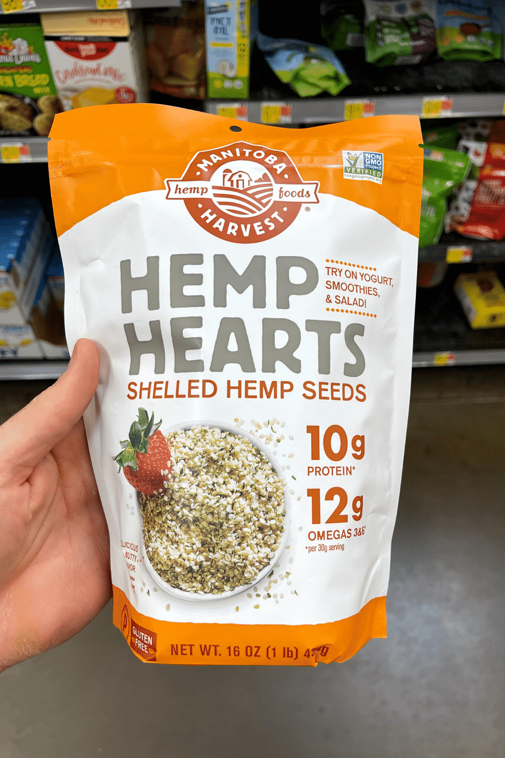 A hand holding a bag of hemp hearts.