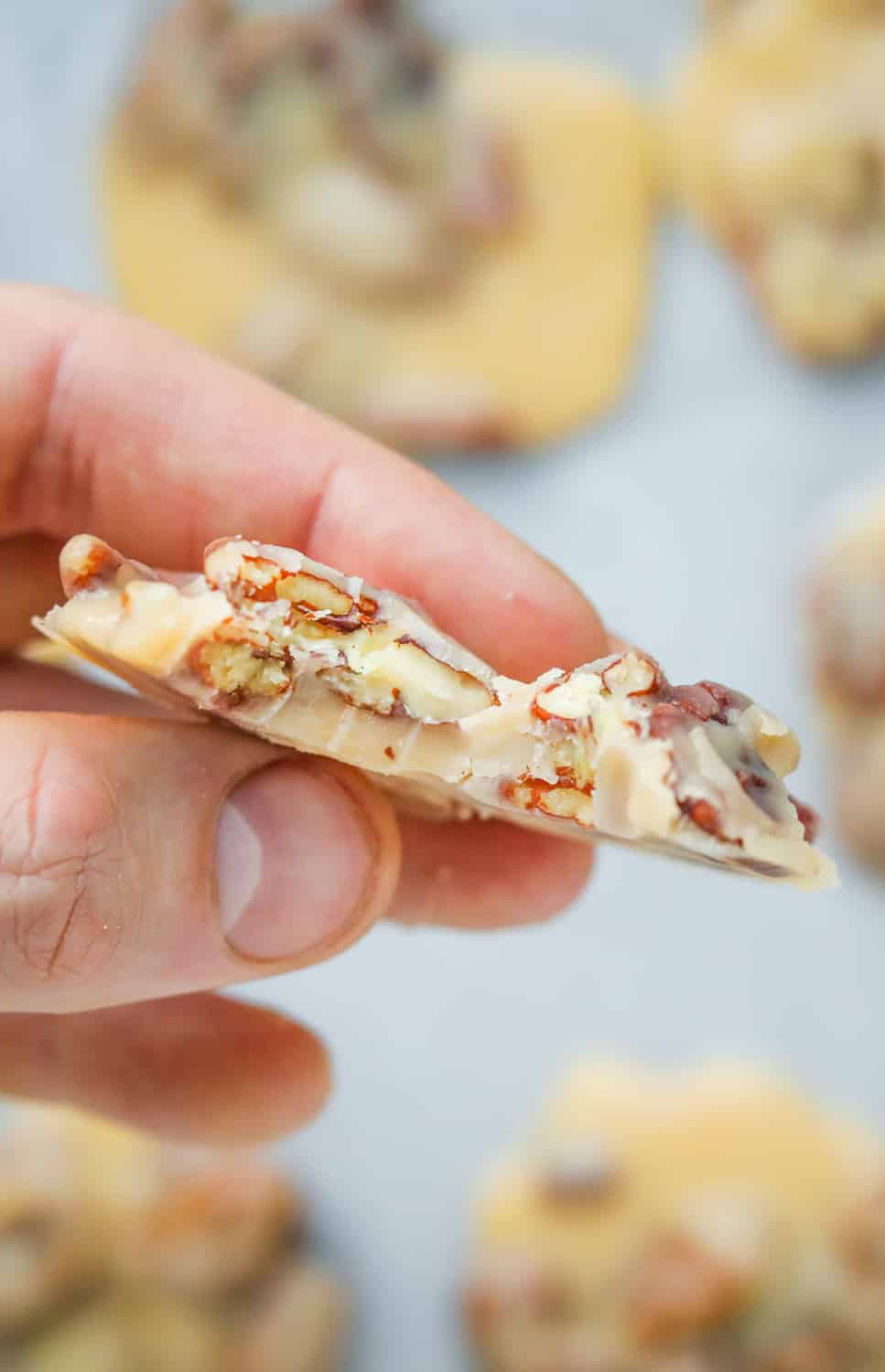 A hand holding a praline with a bite taken out of it.