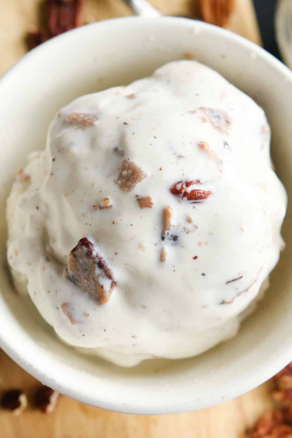 A scoop of pecan filled ice cream in a bowl.