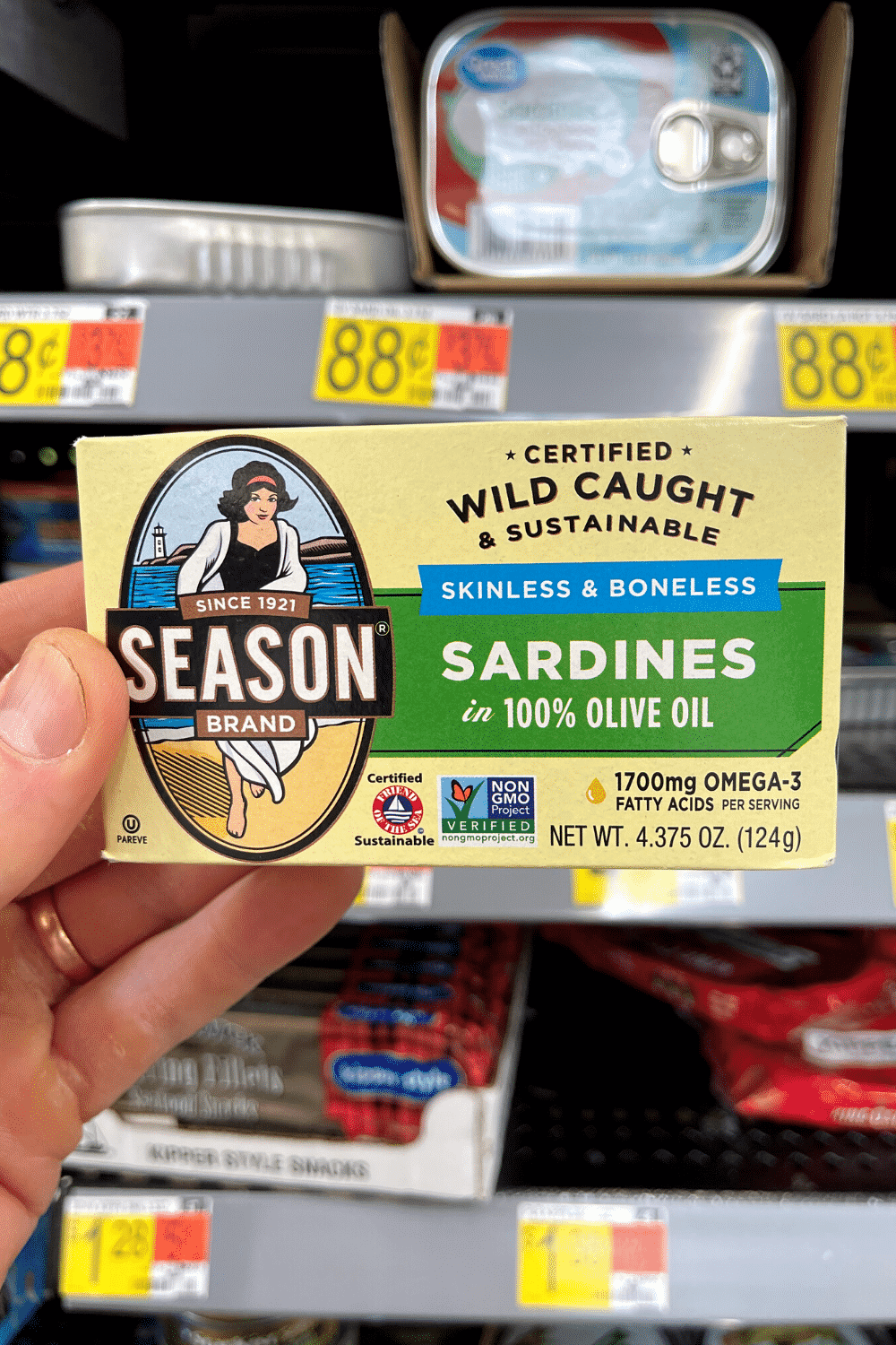 A hand holding a box of sardines.