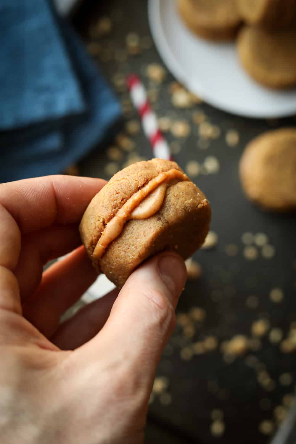 A hand holding a peanut butter cookie that's filled with a peanut butter filling.