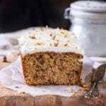 A loaf of carrot cake on a cutting board line with parchment paper.