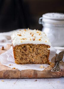 A loaf of carrot cake on a cutting board line with parchment paper.