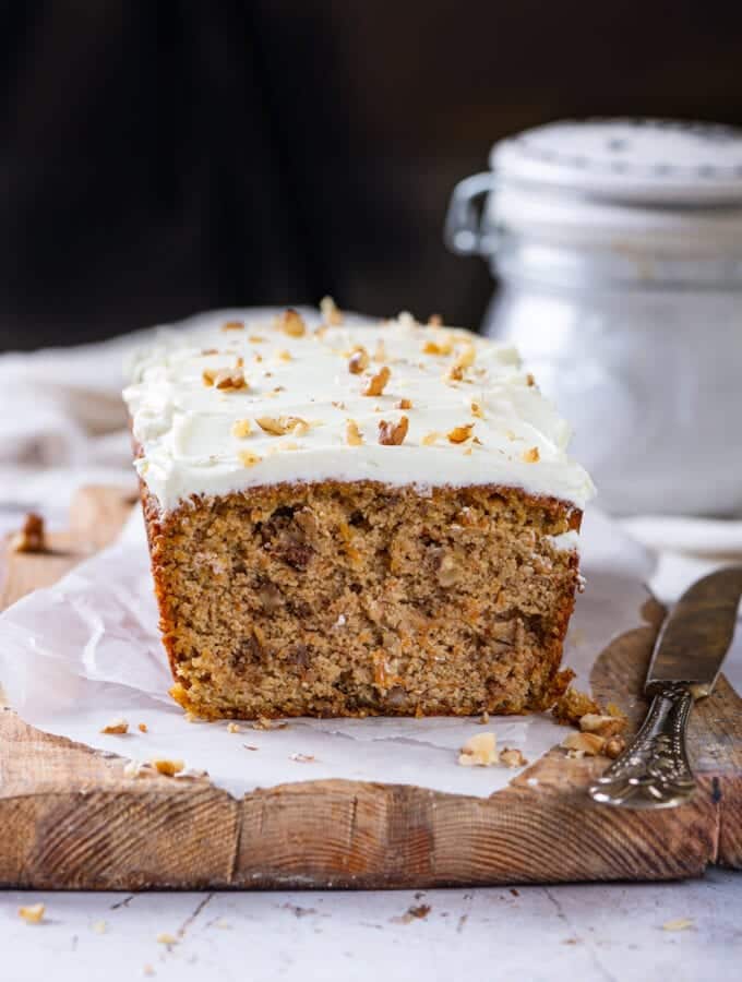 A loaf of carrot cake on a cutting board line with parchment paper.