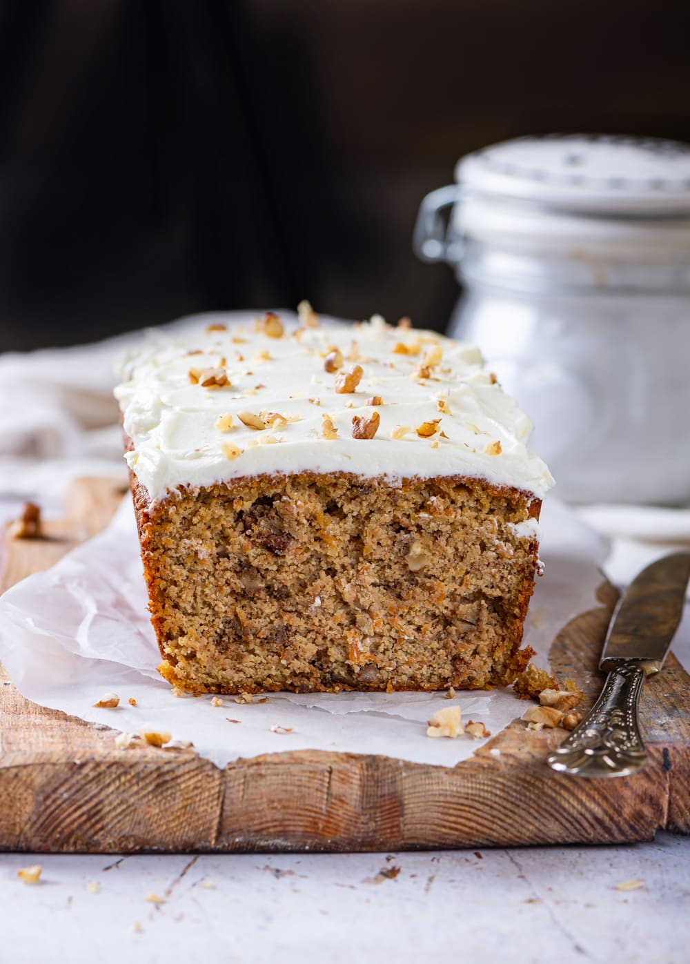 A loaf of carrot cake on a cutting board line with parchment paper.