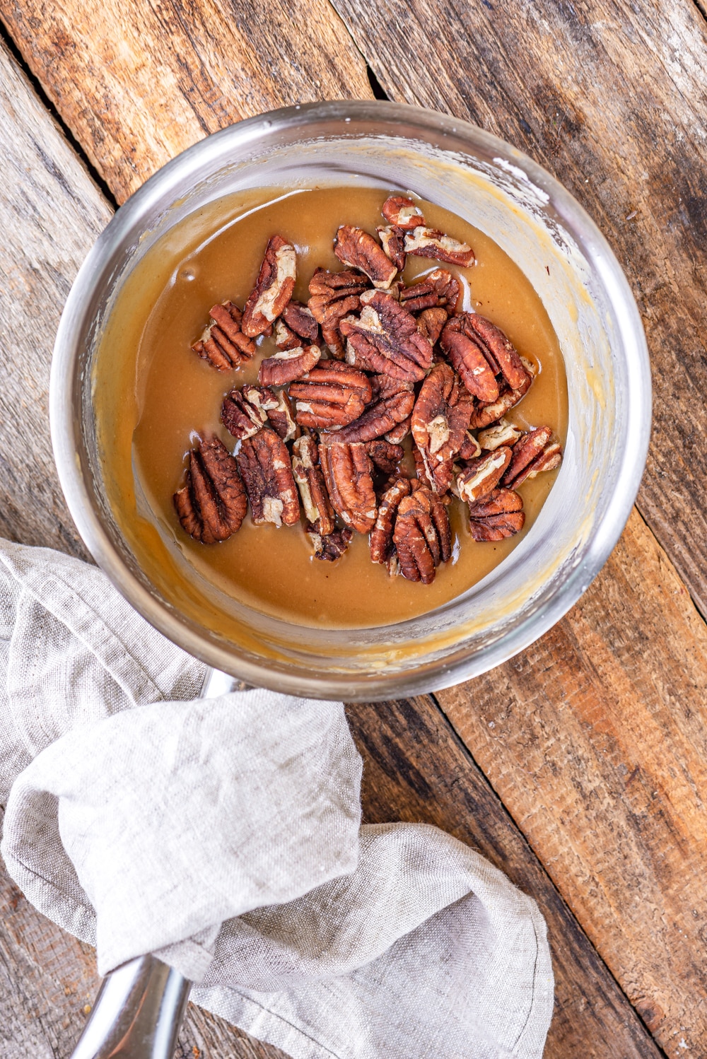 A tin pot filled with caramelized butter and pecans.