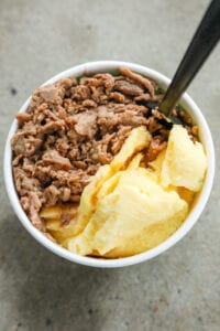 A white cup filled with shredded steak, scrambled eggs, and cheese.