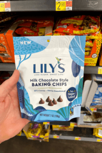 A hand holding a package of sugar-free milk chocolate chips.