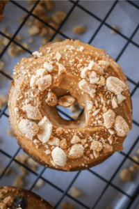 A peanut butter donut on a black wire rack.