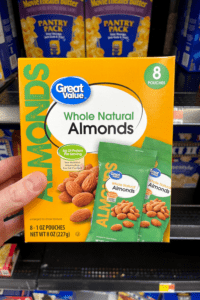 A hand holding a box of raw almond snack packs.