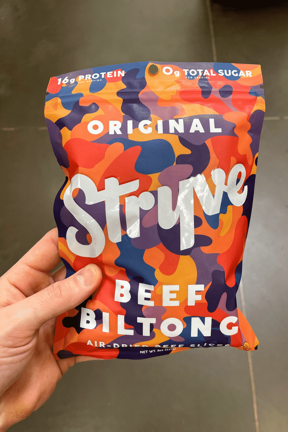 A hand holding a bag of beef biltong.