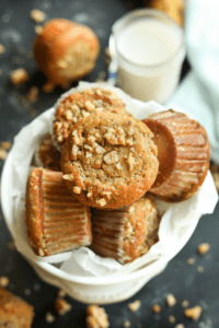 Multiple banana nut muffins on top of each other in a white bowl.