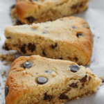 Three chocolate chip scones on a piece of white parchment paper.