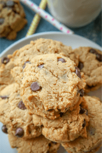 A bunch of peanut butter chocolate chip cookies stacked on top of one another on a white plate.