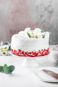 An entire red velvet cake on a white serving tray.