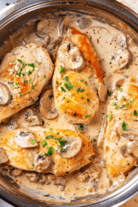 A pan with four pieces of chicken marsala in it.