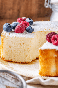 A angel food cake with a slice taken out of the front of the cake.