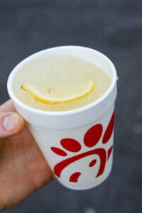 A hand holding a cup of lemonade from Chick-Fil-A.