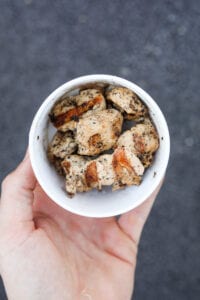 A hand holding a cup filled with grilled chicken nuggets from Chick-Fil-A.