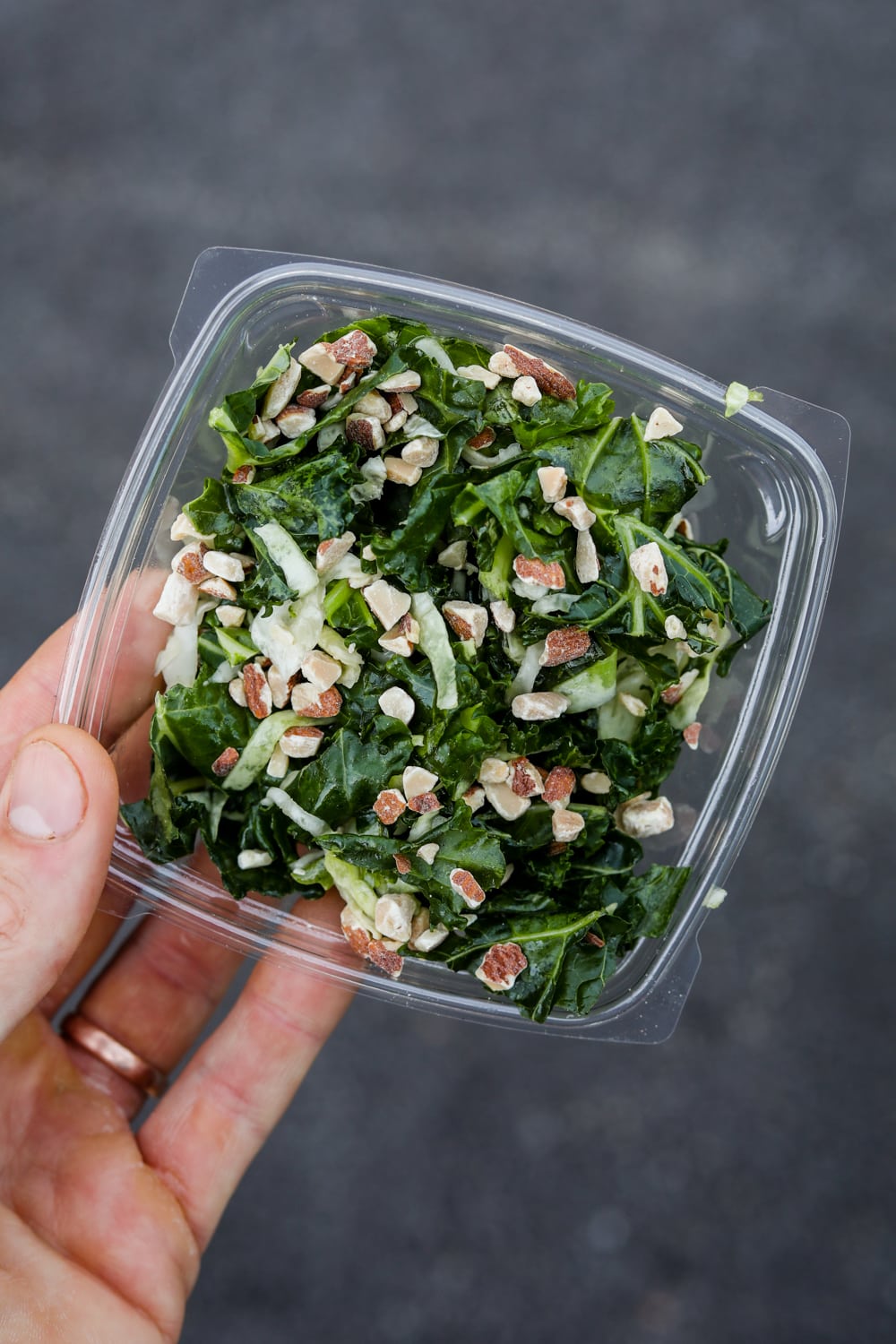 A hand holding a container of kale crunch salad from Chick-fil-A