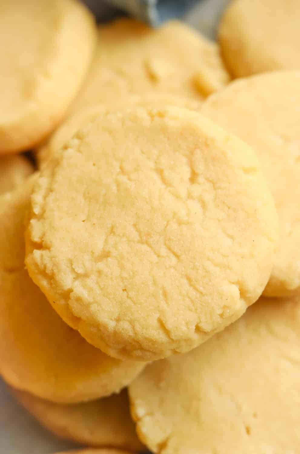 A pile of lemon cookies stacked on top of one another with a blue napkin in back of them.