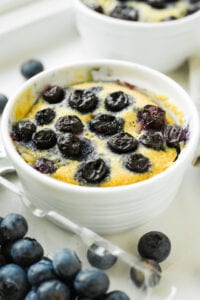 A blueberry muffin in a white mug.