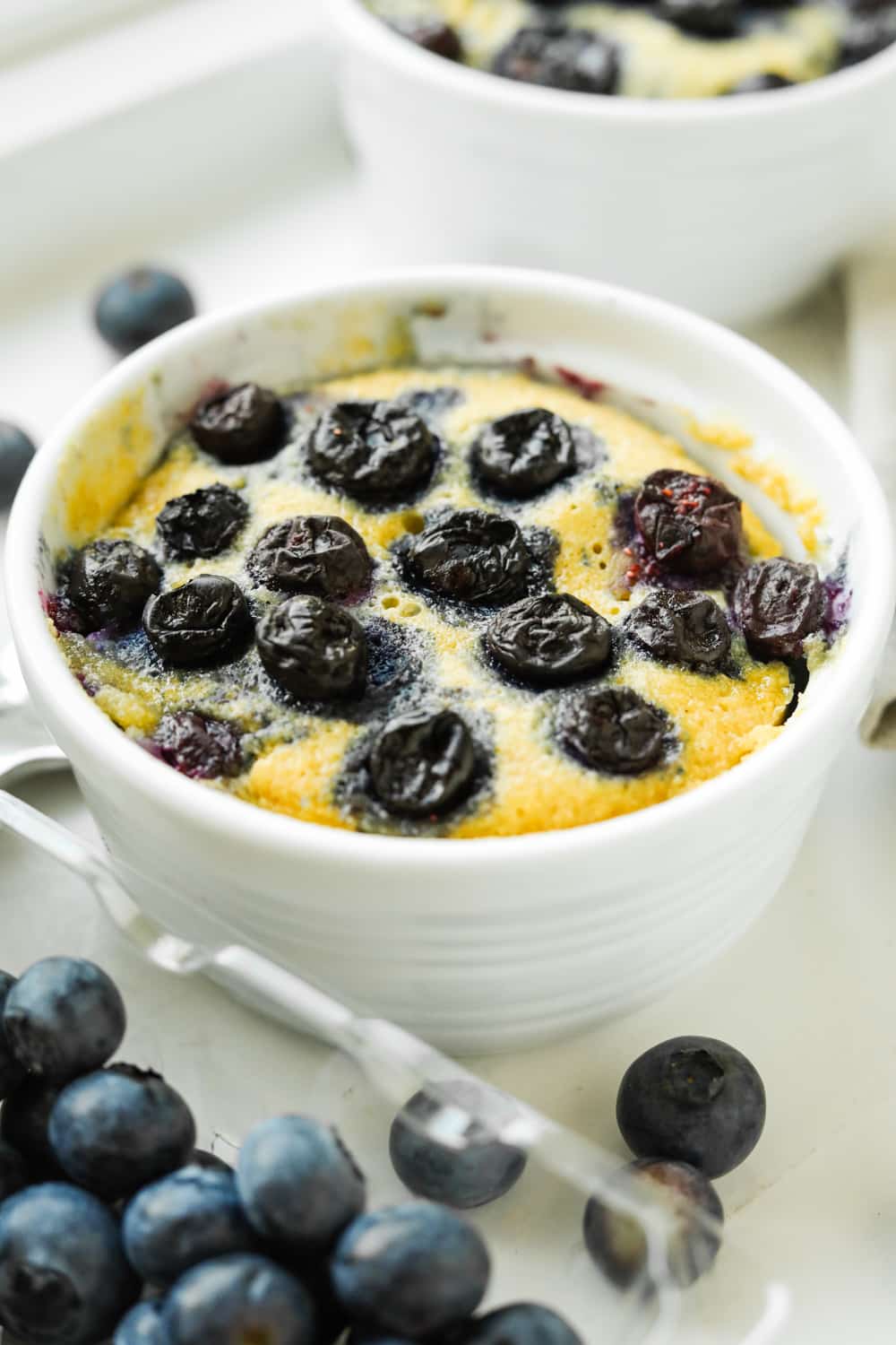 A blueberry muffin in a white mug.