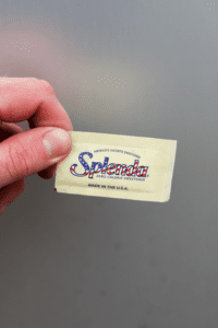 A hand holding a packet of Splenda sweetener.