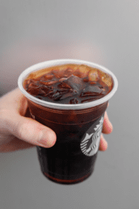 A hand holding a cup of Starbucks iced coffee.