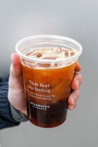 A hand holding a cup of Starbucks iced shaken espresso.