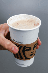 A hand holding a cup of Starbucks keto cinnamon dolce latte.