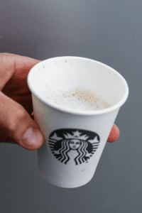 A hand holding a cup of Starbucks keto espresso macchiato.