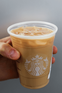 A hand holding a cup of Starbucks keto iced blonde vanilla latte.