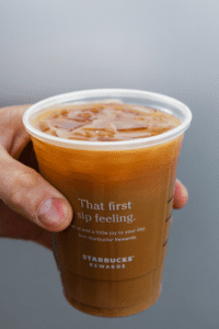 Hand holding a cup of Starbucks keto iced flat white.