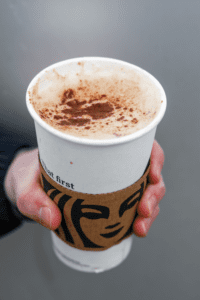 A hand holding a cup of Starbucks cinnamon dolce latte.