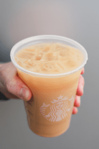 A hand holding a cup of Starbucks iced royal English breakfast tea latte.